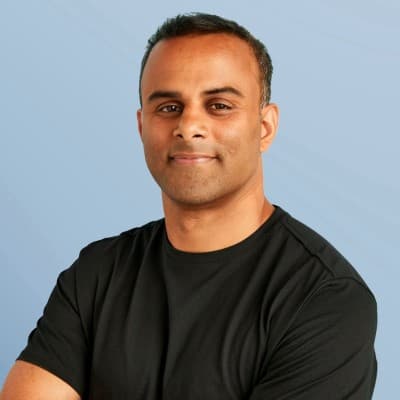 Dwayne D'Souza in a black T-shirt against a pale blue background.