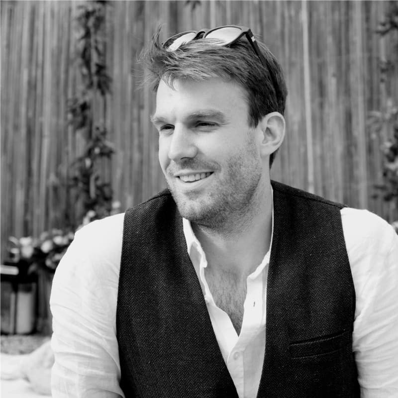 Stu Peak in a black sweater with bookshelves in the background.